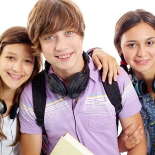Cute teens with headphones smiling at camera